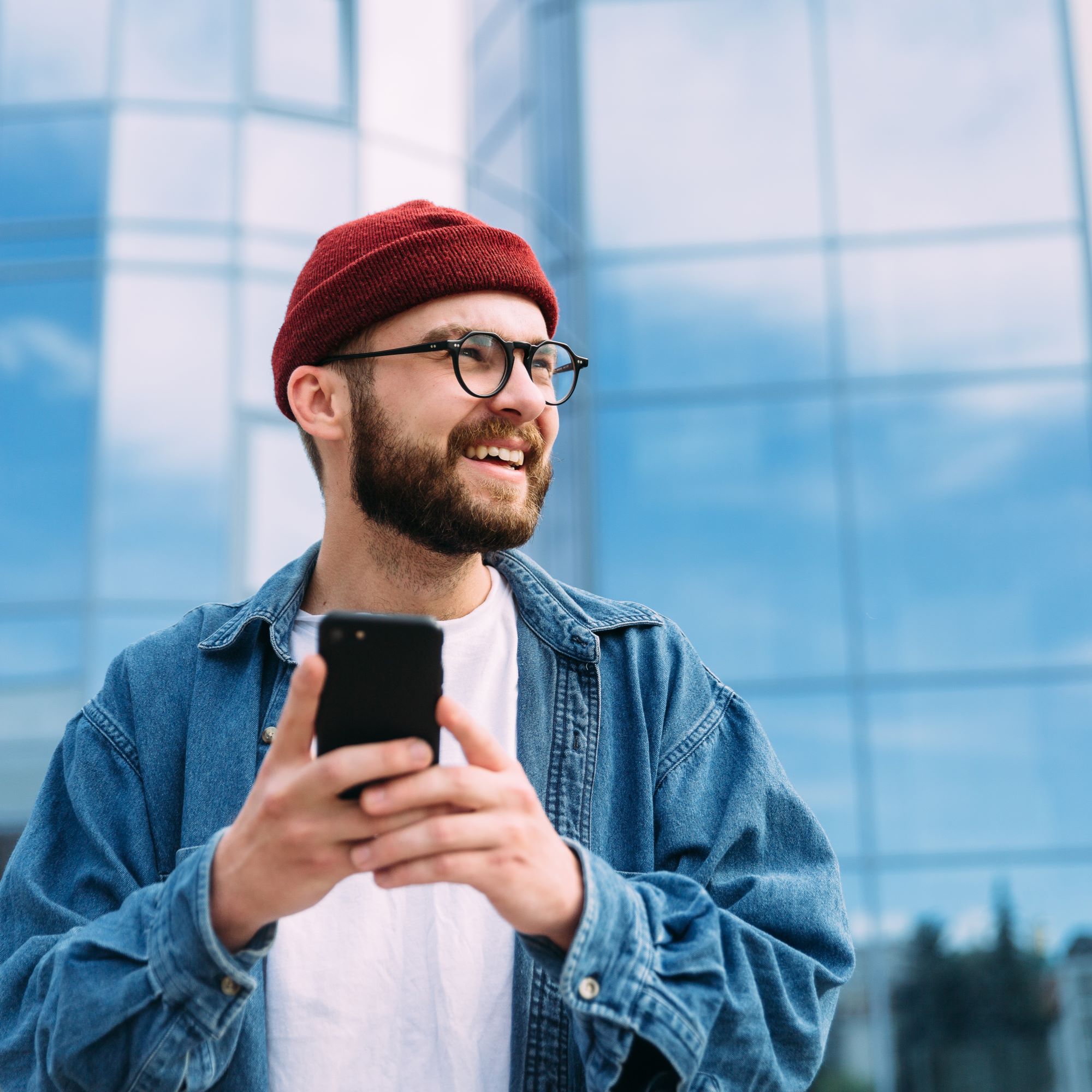 Man on his phone in front of a large building. Clinsura allows Medicaid recipients to make a self-referral, meaning they can take control of their care coordination.