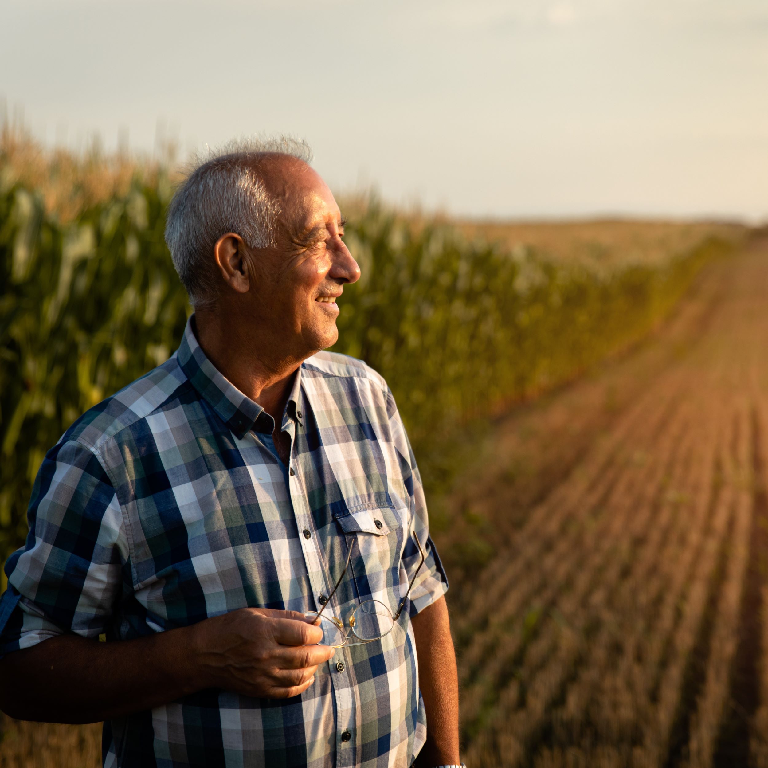 Older man standing in front of a corn field. Clinsura offers home-based care coordination and mental health counseling for Medicaid recipients and people from underserved communities in Minnesota.